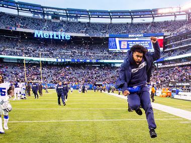Dallas Cowboys running back Ezekiel Elliott, who was inactive for the game, celebrates as he...