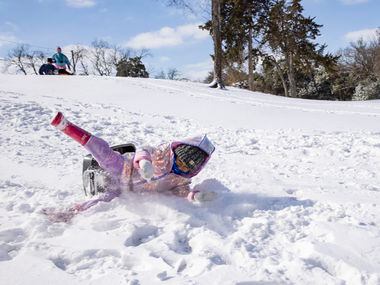 Mia Donjuan, 4, wipes off of her pan as she slides down a hill in the Dallas Elmwood...
