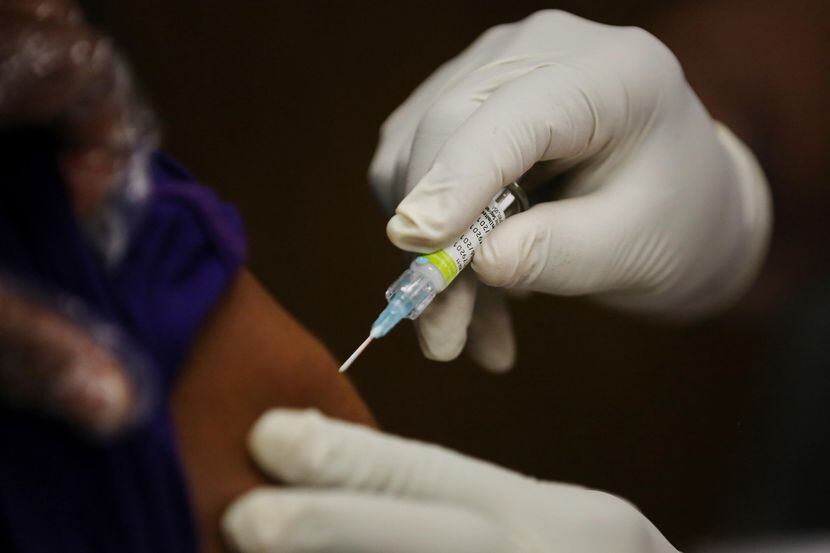 Una enfermera administra la vacuna contra la influenza a un paciente en un centro para...