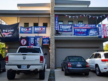 Neighbors in a two-story apartment have competing Biden and Trump banners draped over their...