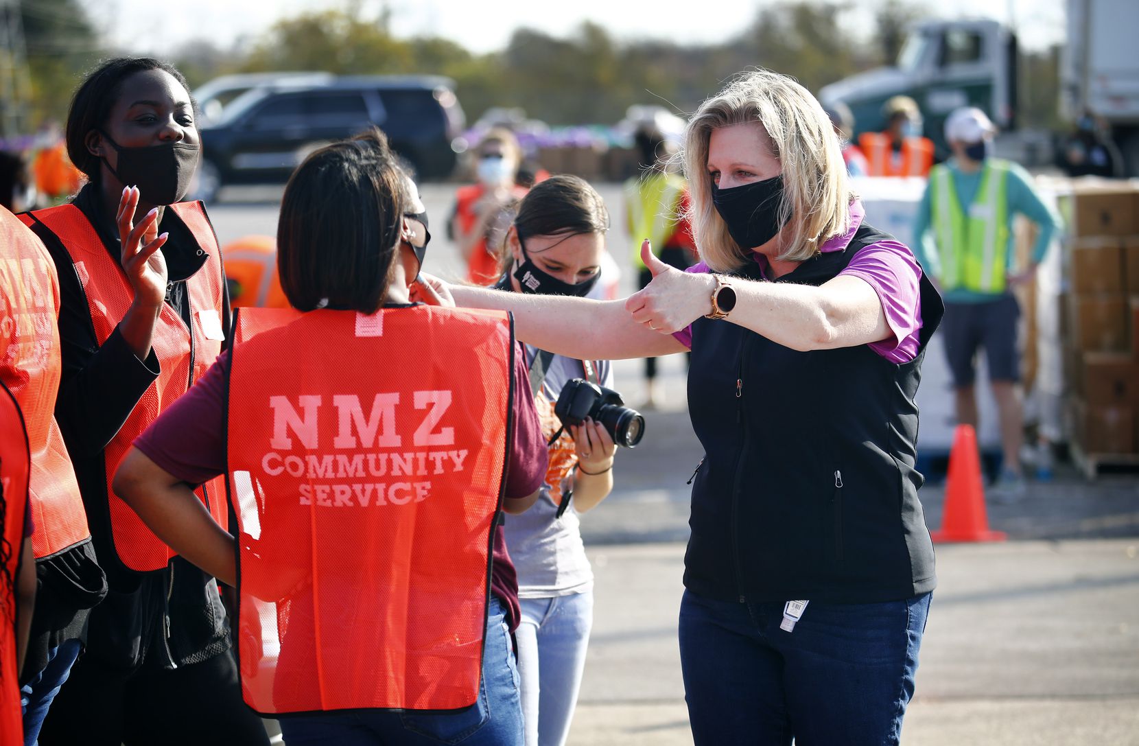 North Texas Food Bank CEO Trisha Cunningham (right) gives a thumbs up to volunteers Brittany Kennedy (left) and Lacy Ware (center) as they distributed food to families lined up at Fair Park in Dallas in November. 