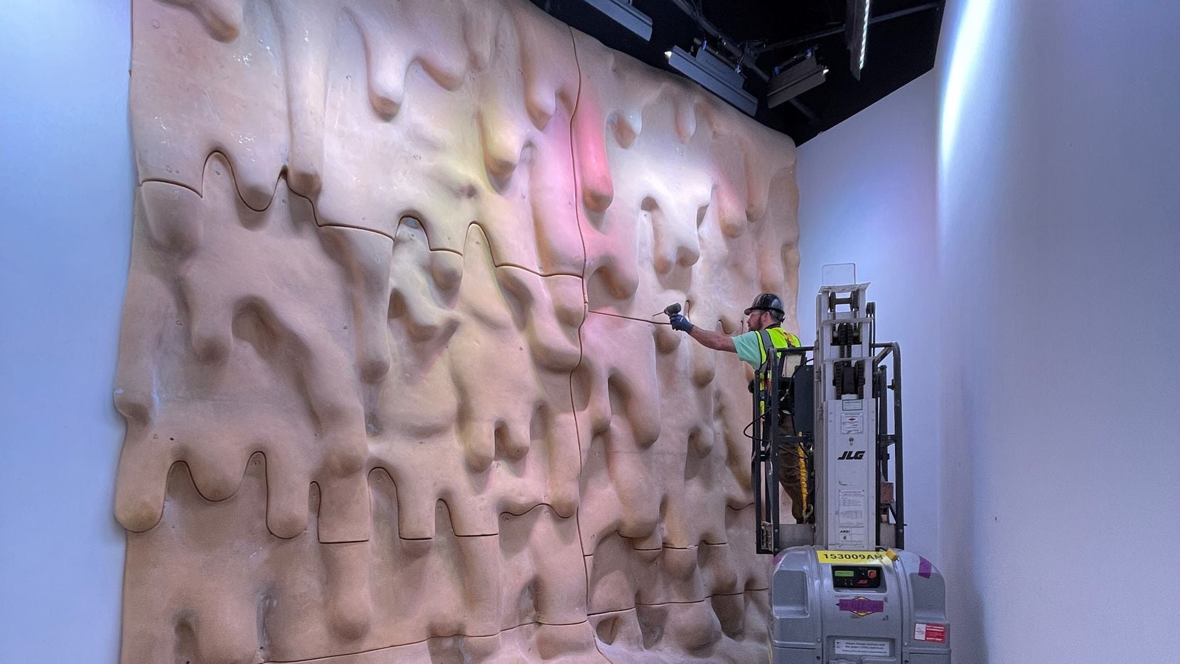A crew works to install Dan Lam's dripping wall design at Meow Wolf Grapevine. The immersive...