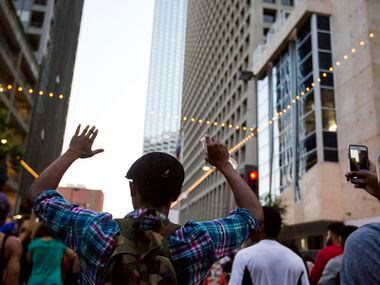 Demonstrators raise their hands during a Black Lives Matter march down Main Street in...