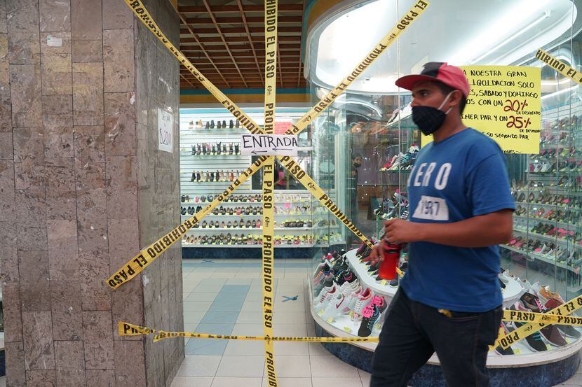 Una persona camina frente a una zapatería cerrada en la Ciudad de México como una medida de...
