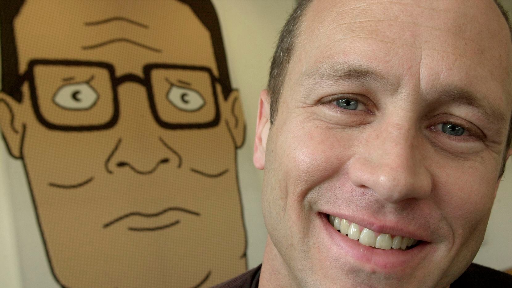 Mike Judge poses in front of an illustration of Hank Hill in 2002 in Los Angeles. Judge and...