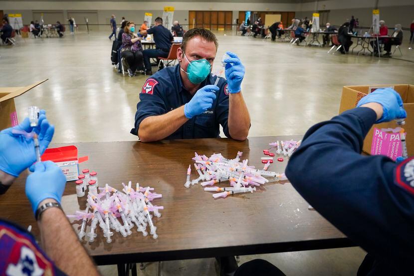 Arlington Fire Department captain K.J. Land  prepares doses of the Moderna COVID-19 vaccine...