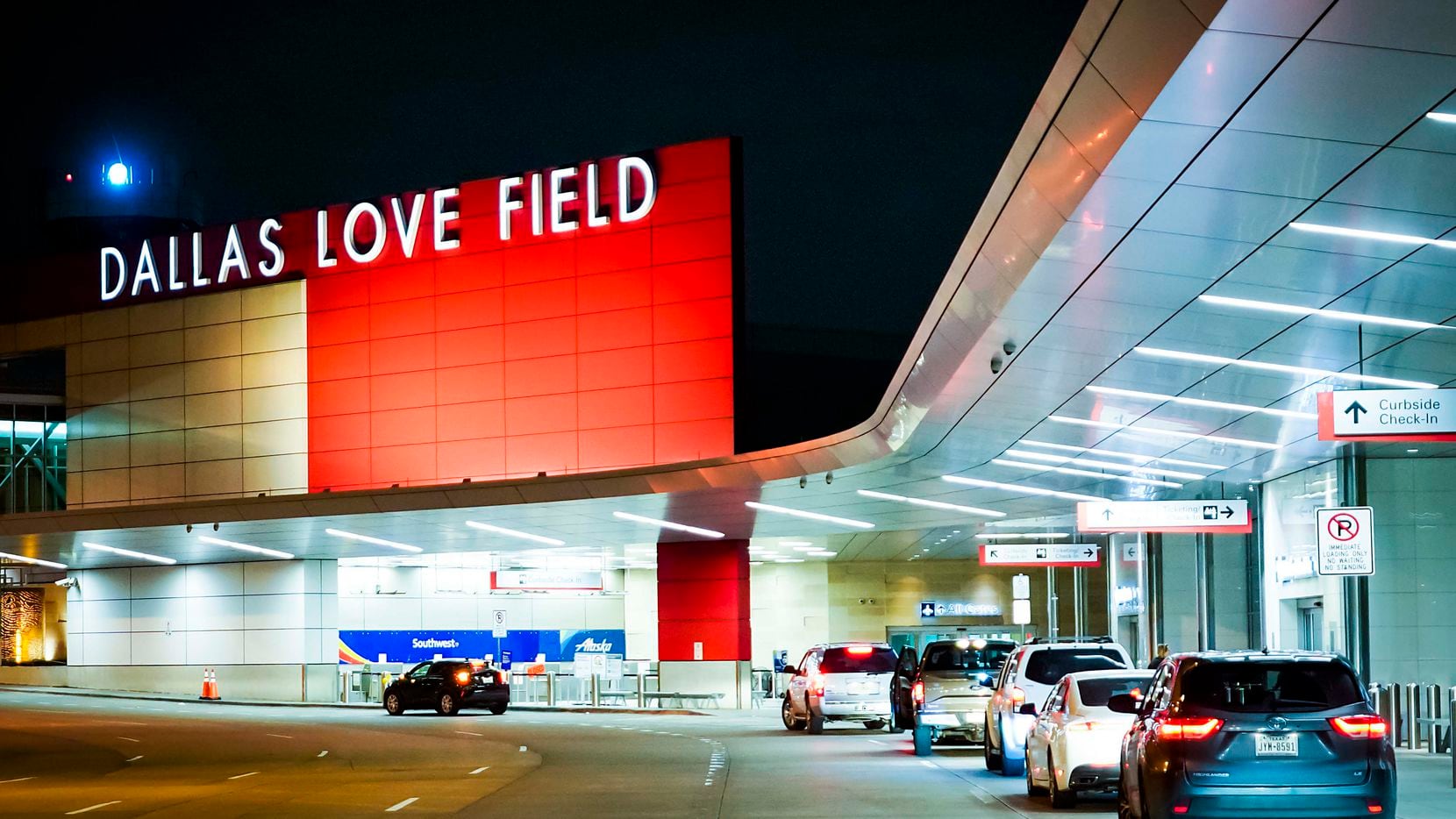 Cars pull up to the lightly trafficked departures curbside in front of Dallas Love Field airport on Friday, March 20, 2020, in Dallas.