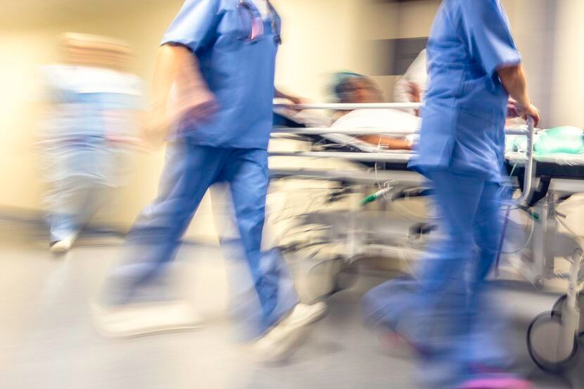 Doctores y enfermeras  transportan a un paciente en una camilla hacia un hospital.