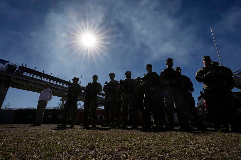 Elementos de la Guardia Nacional de pie mientras el gobernador de Texas Greg Abbott y otros...