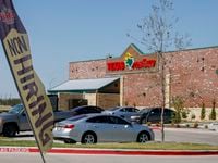 A now hiring sign flys outside a Texas Roadhouse at the Crossroads at Terrell shopping...