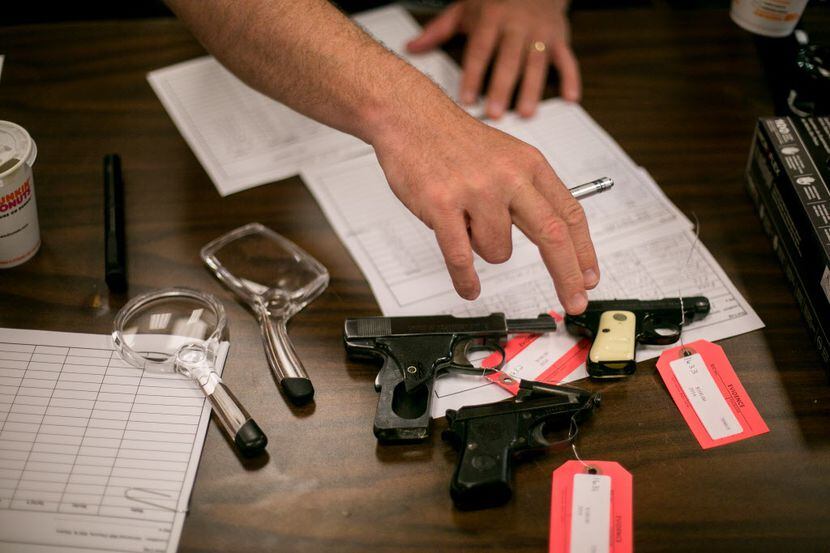  A police officer processes guns turned in during a buyback event at Universal Missionary...
