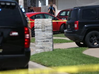 A crime scene photographer takes a photo of a vehicle in the driveway of the Ponder home...