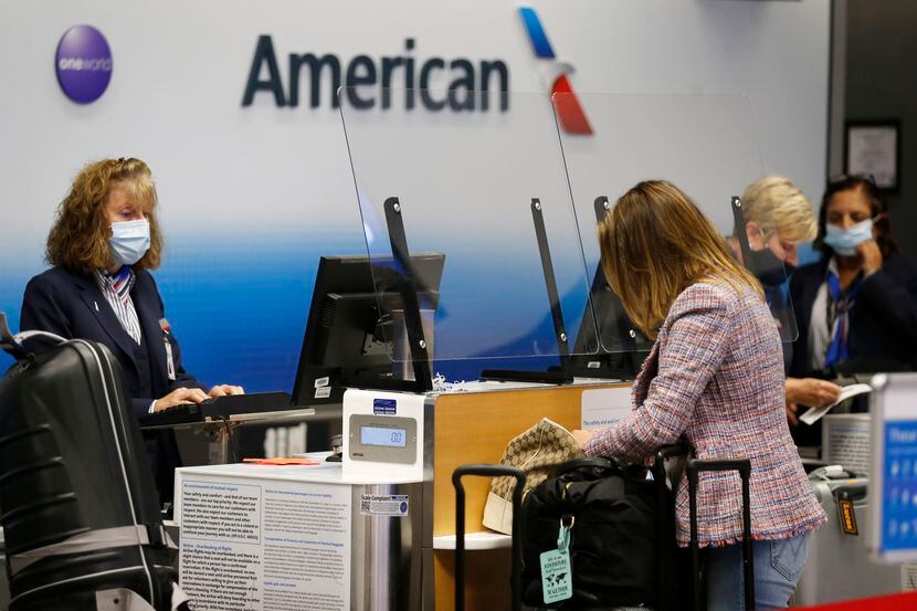 Agentes de American Airlines ayudan a procesar el pase de abordar de pasajeros en la...