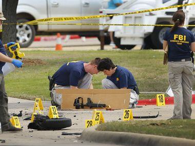 Members of the FBI Evidence Response team box up a  rifle and clip as they document the...