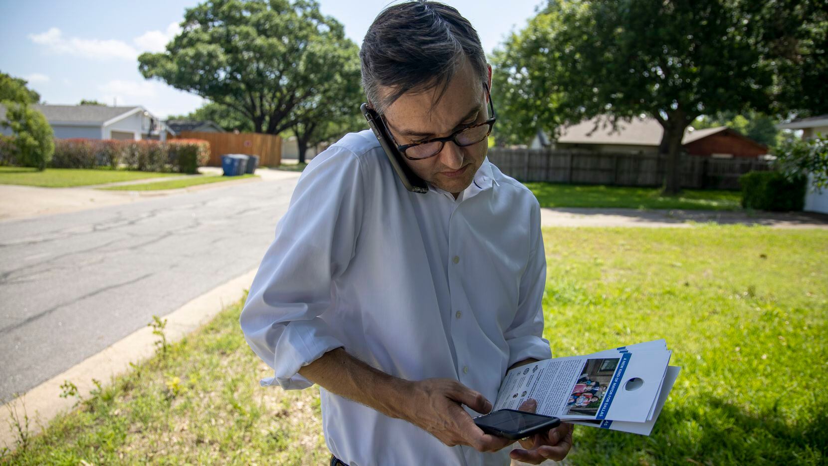 Mayoral candidate Scott Griggs answers a call as he checks a voter database on a second smartphone while block-walking in Lake Highlands on Friday, May 24. (Shaban Athuman/Staff Photographer)
