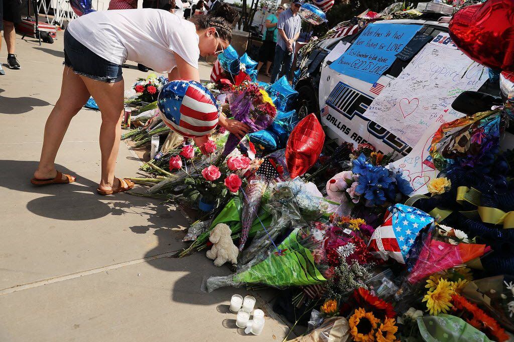 People contribute to the growing memorial at Dallas police headquarters. 