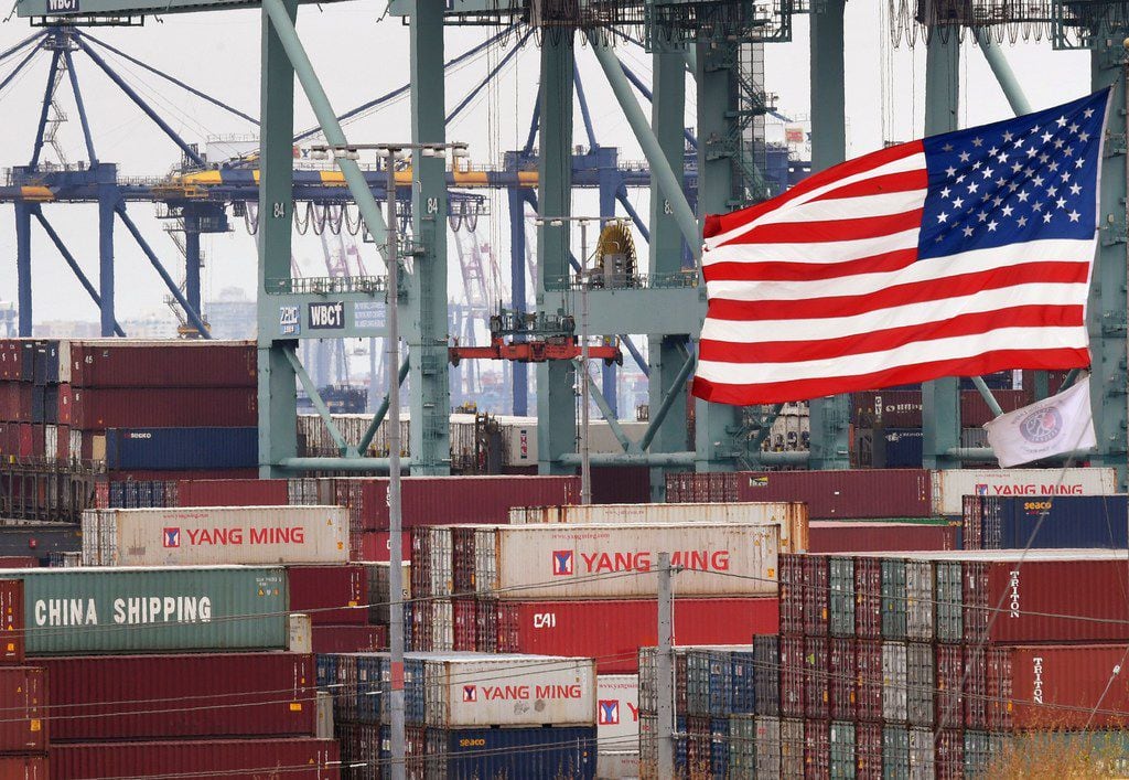 Chinese shipping containers are stored beside a US flag after they were unloaded at the Port...