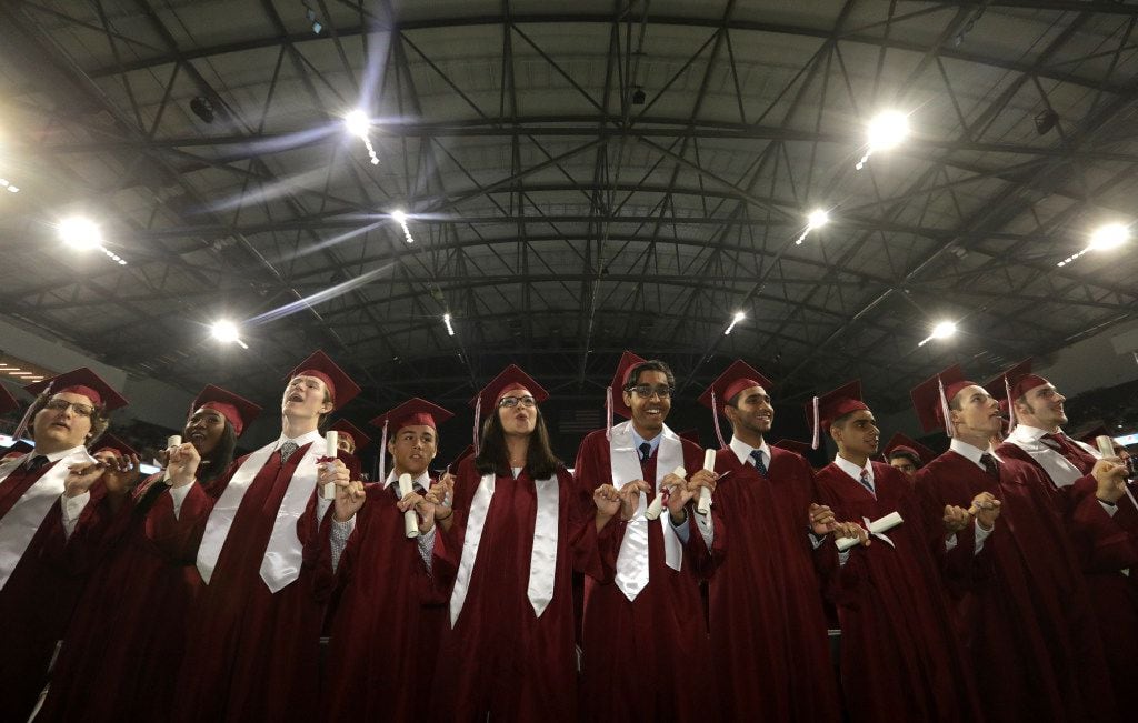 Graduates sing the school song during Plano Senior High School's graduation ceremony at The...