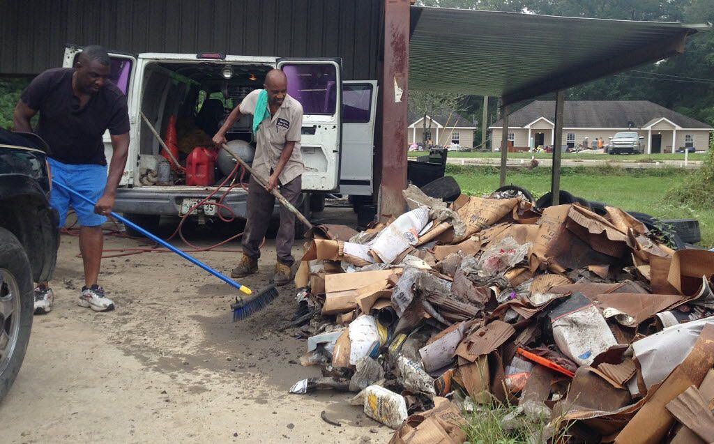 Terry Brewer (left) and Timothy Harris piled up debris outside a flooded auto parts store in...