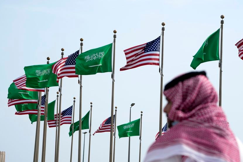 Un hombre camina bajo banderas estadounidenses y de Arabia Saudita previo a la visita del...