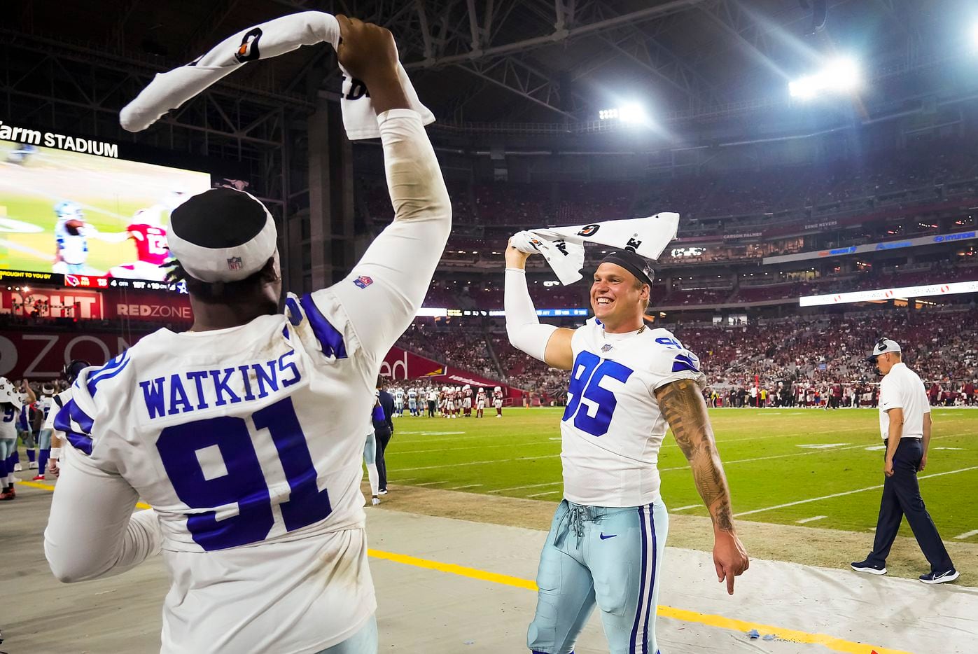Dallas Cowboys defensive end Brent Urban (95) and defensive end Carlos Watkins (91) wave towels on the sidelines after a Cowboys touchdown during the second half of a preseason NFL football game against the Arizona Cardinals at State Farm Stadium on Friday, Aug. 13, 2021, in Glendale, Ariz.
