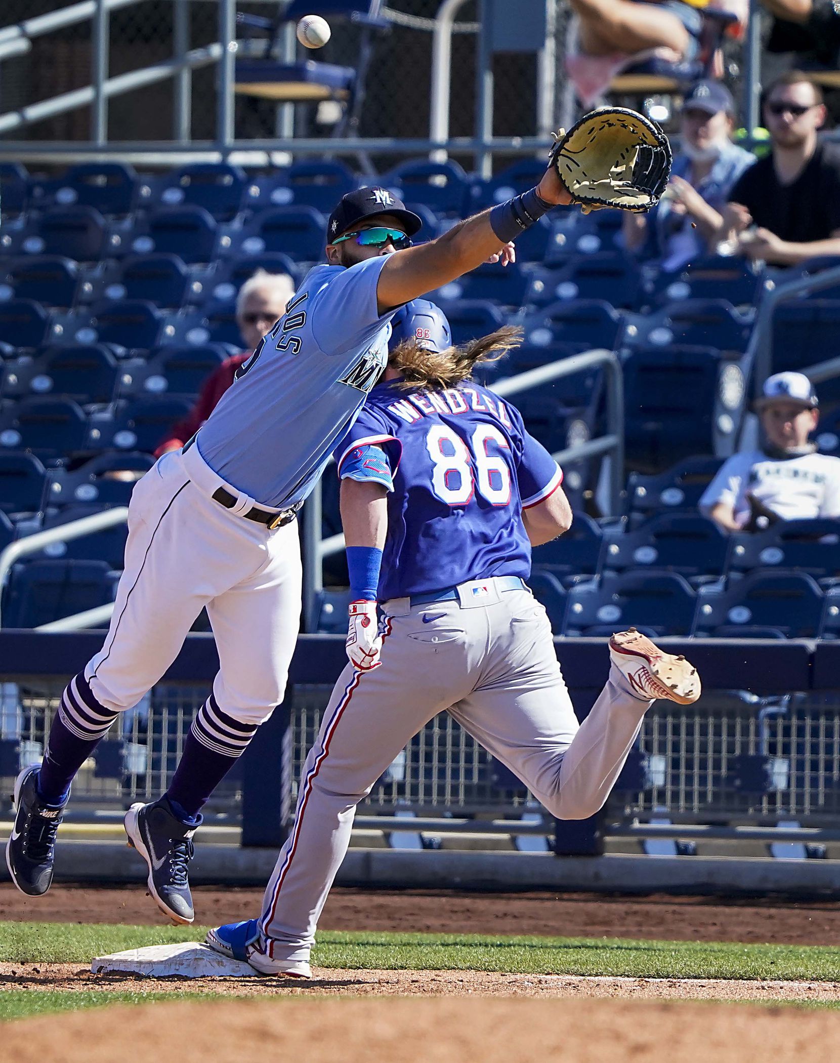 Texas Rangers infielder Davis Wendzel is safe at first base with a single as the ball gets away from Seattle Mariners first baseman Jose Marmolejos during the fifth inning of a spring training game at Peoria Sports Complex on Wednesday, March 10, 2021, in Peoria, Ariz.