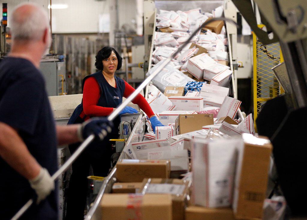 Mail handlers Elizabeth Ransom and Mark Pruett fill and sort priority mail packages on a...