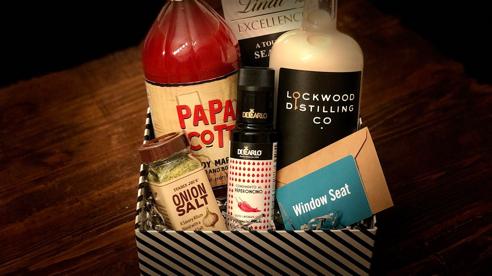 How do you assemble the perfect holiday gift basket? Fill it with a mix of local and not-local foodie finds. Sarah Blaskovich's 2021 holiday gift baskets are (from top left): Papa Scott's bloody Mary mix; Lindt's "a touch of sea salt" chocolate; Lockwood Distilling Co.'s bourbon cream liqueur; a gift certificate to a locally-owned restaurant or coffee shop, like Window Seat in East Dallas; a bougie bottle of spicy olive oil from Eataly; and a shaker of onion salt from Trader Joe's.