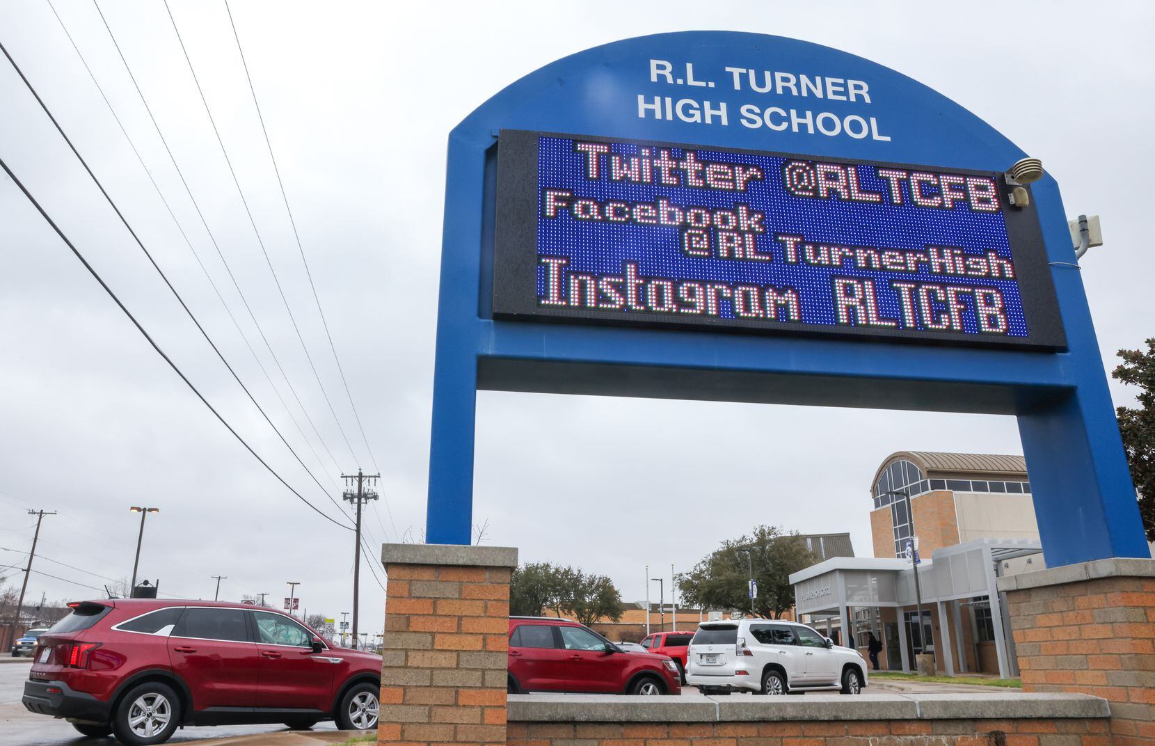 Cars waited outside of Carrollton-Farmers Branch ISD’s R. L. Turner High School for...