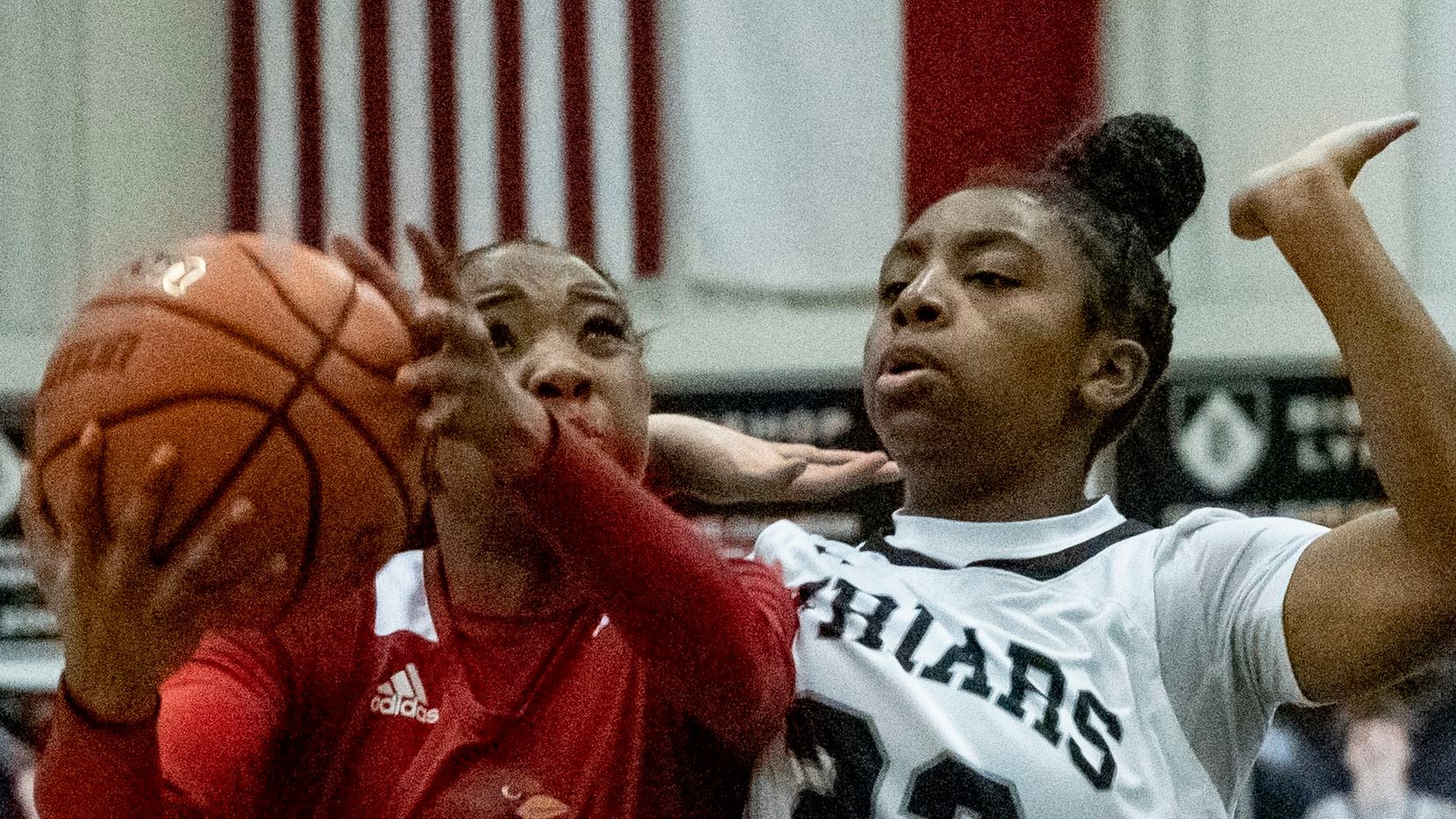 John Paul II's Sydney Wade (2) holds the ball away from Bishop Lynch's Mikah Ford (23)...