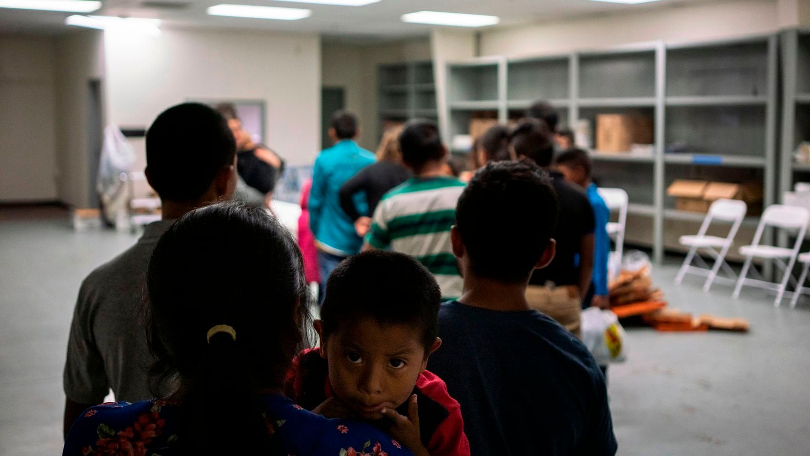 Varias familias formadas en la línea para recibir comida en la Casa del Refugiado, un centro...
