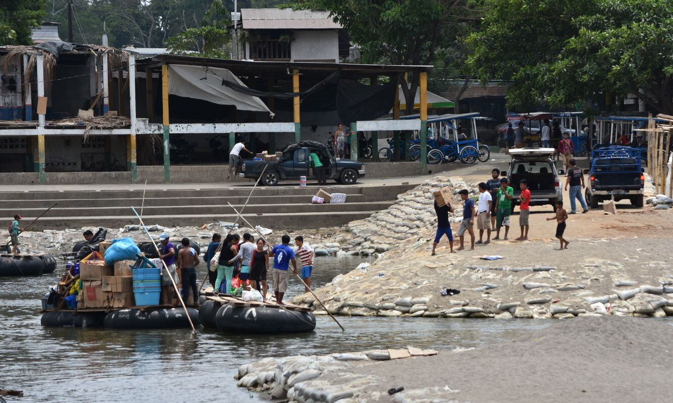 Varias personas intentan cruzar de Guatemala a México en una balsa hechiza por el Río Suchiate, en Chiapas.