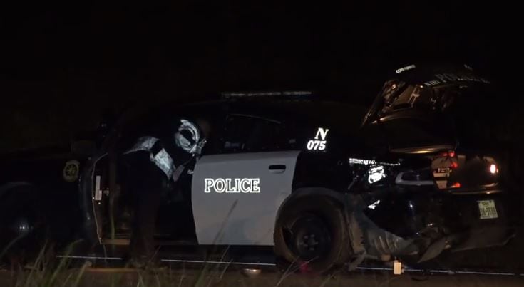 A Fort Worth police officer exams a patrol car that was involved in a crash with a fleeing...