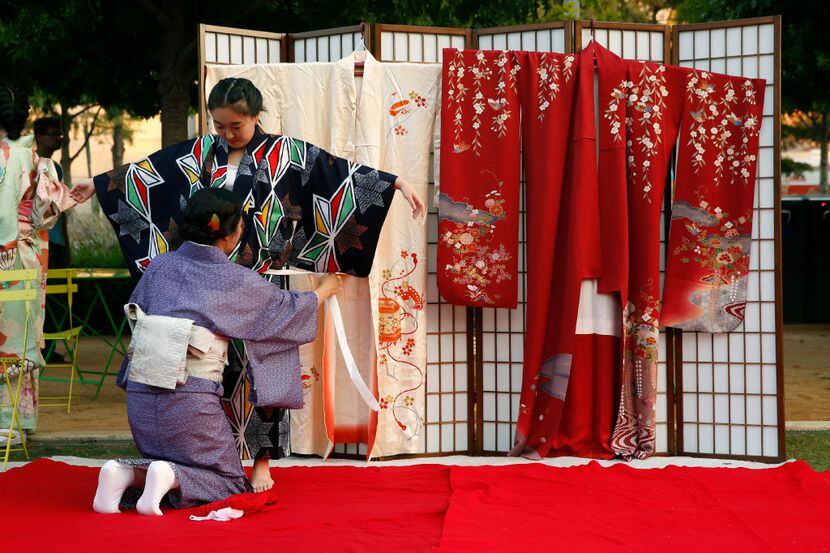 Yuki Takamatsu (standing) is dressed in a kimono by Sumiko Hashimoto during a demonstration...