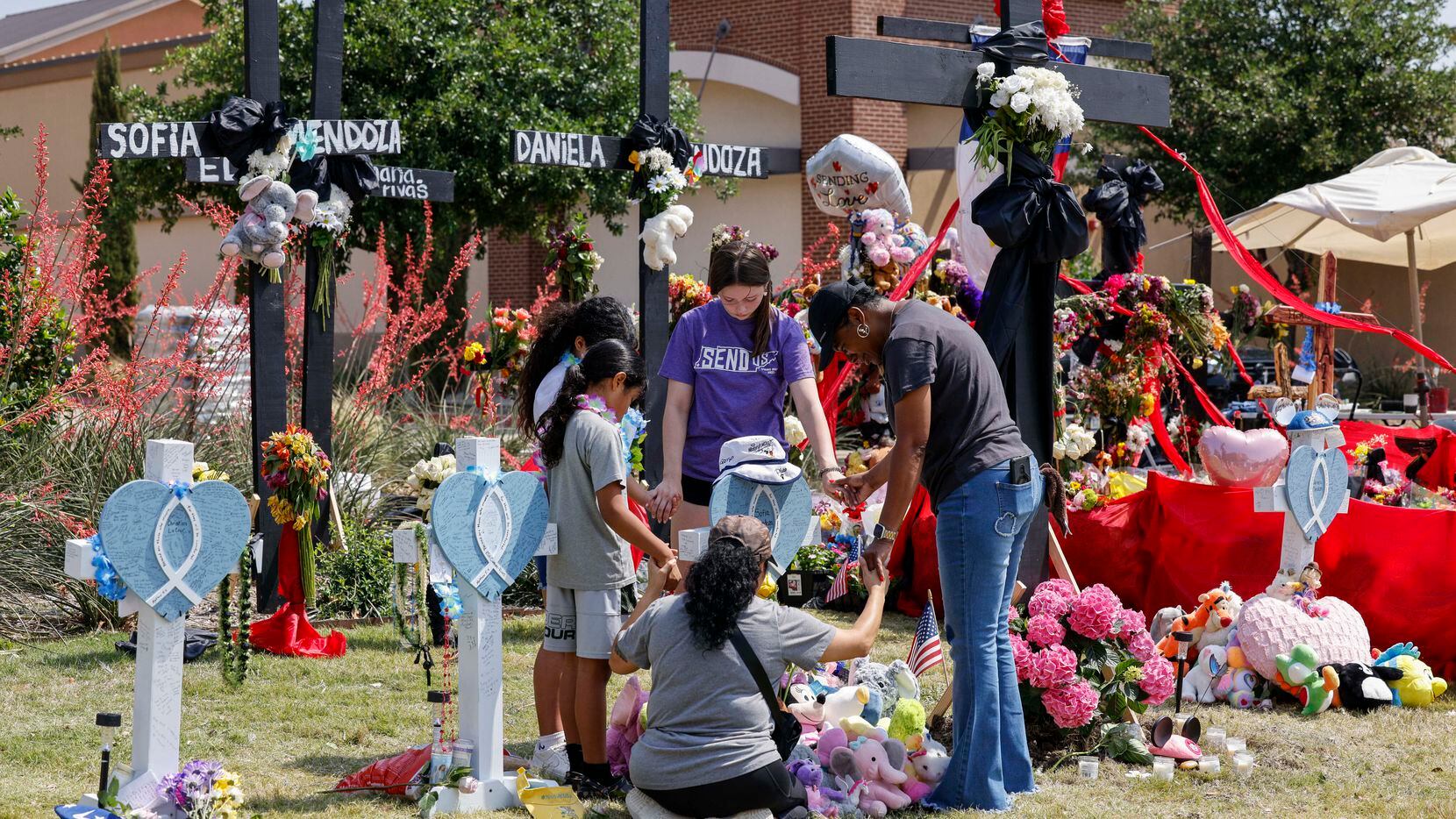 People pray around a cross for Sofia Mendoza, 8, at a memorial on Tuesday, May 9, 2023, for...
