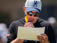 Dallas Cowboys offensive coordinator Kellen Moore talks on a radio during a practice at...