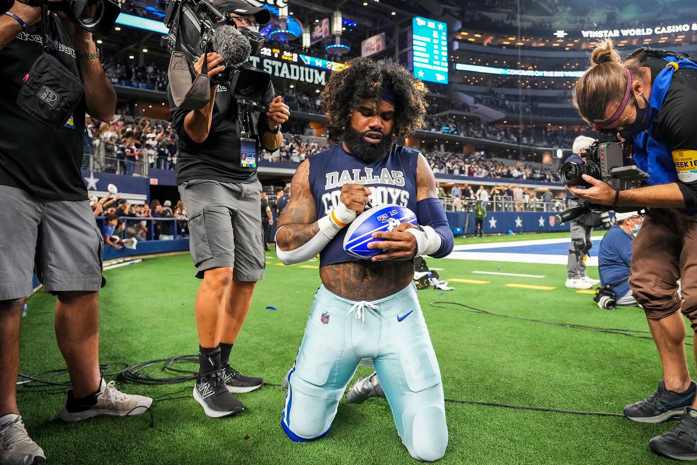 Dallas Cowboys running back Ezekiel Elliott autographs a football for a fan as he leaves the field following a victory over the Washington Football Team in an NFL football game at AT&T Stadium on Sunday, Dec. 26, 2021, in Arlington. The Cowboys won the game 56-14.