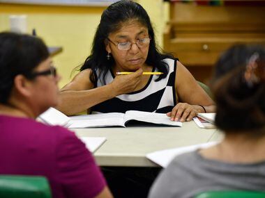 Angelina Alvarado, 60, of Dallas, follows along from a book during a citizenship class at...