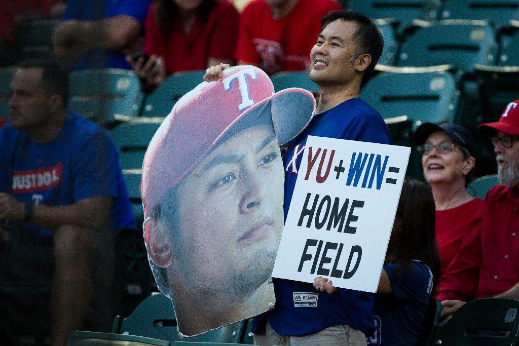 A fan holds signs in support of Texas Rangers starting pitcher Yu Darvish before a game...