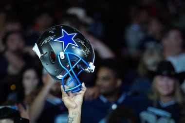 A Dallas Cowboys fan holds up a helmet as fans await the team’s first round pick in the NFL...