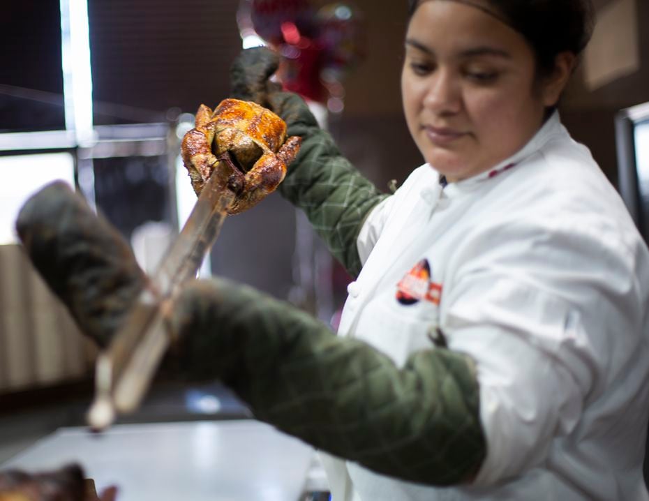 Jenny Lopez takes the pollo a la brasa (Peruvian roasted chicken) out of the oven at the...