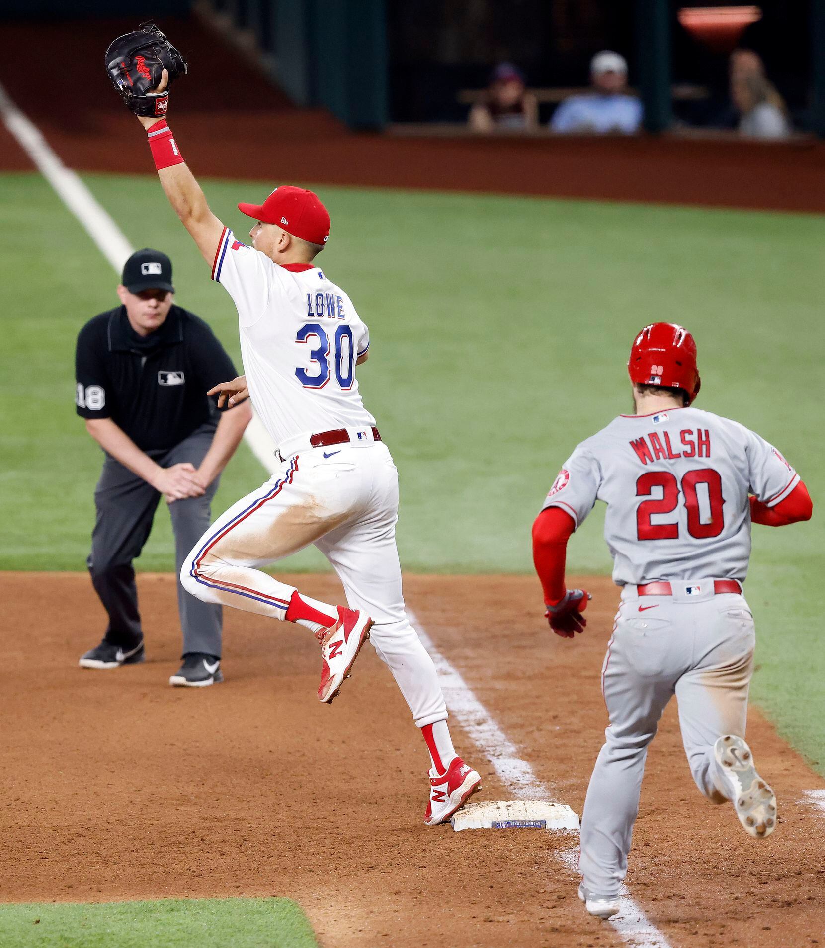 Texas Rangers first baseman Nate Lowe (30) reaches high the catch a batted ball by Los Angeles Angels Jared Walsh (20) during the eighth inning at Globe Life Field in Arlington, Texas, Wednesday, April  28, 2021. (Tom Fox/The Dallas Morning News)