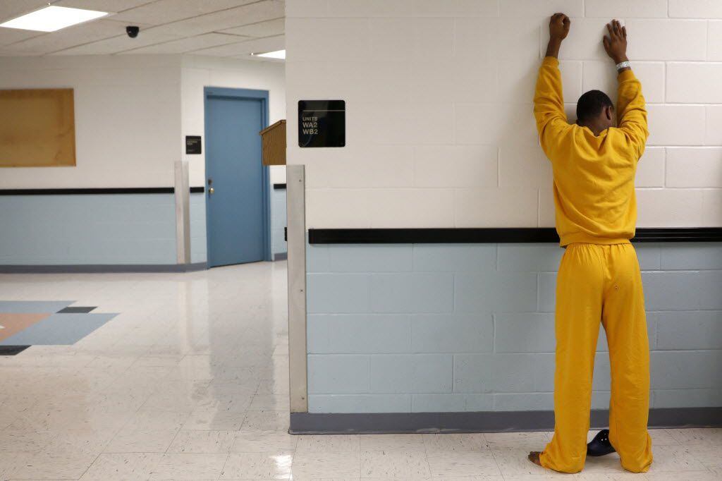 A juvenile inmate places his hands against the wall for a routine search at the Henry Wade Juvenile Justice Center in Dallas.
