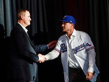 Corey Seager shakes hands with Chris Young at a news conference at Globe Life Park in...