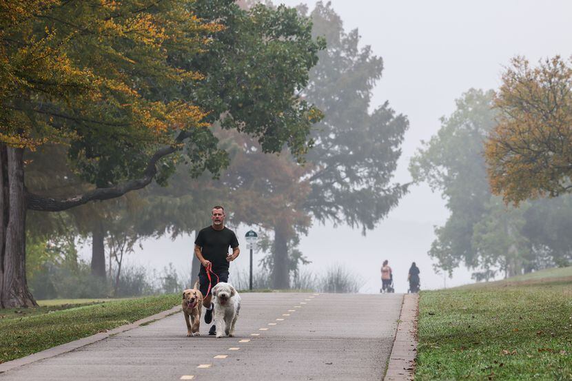 David White with Gus and Lucky jog around White Rock Lake in Dallas during a foggy morning...