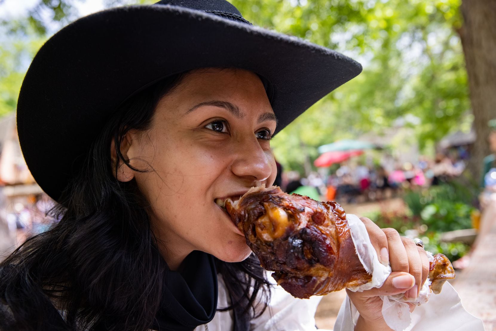 Nelly Hernandez of Arlington bites into a turkey leg. Other festival foods include Scottish...