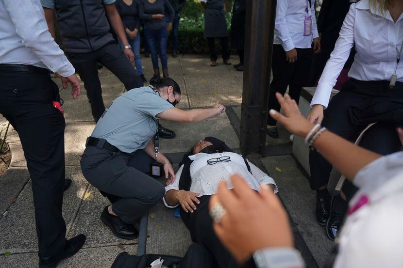 Una mujer es asistida por ansiedad mientras la gente se reúne en la calle luego de un...