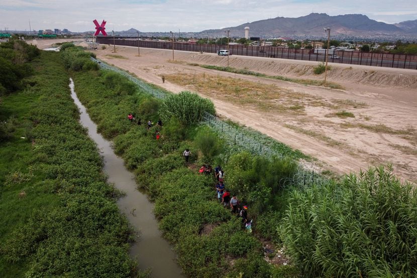 Migrants arriving in Juarez seek refuge along the banks of the Rio Grande near the towering...