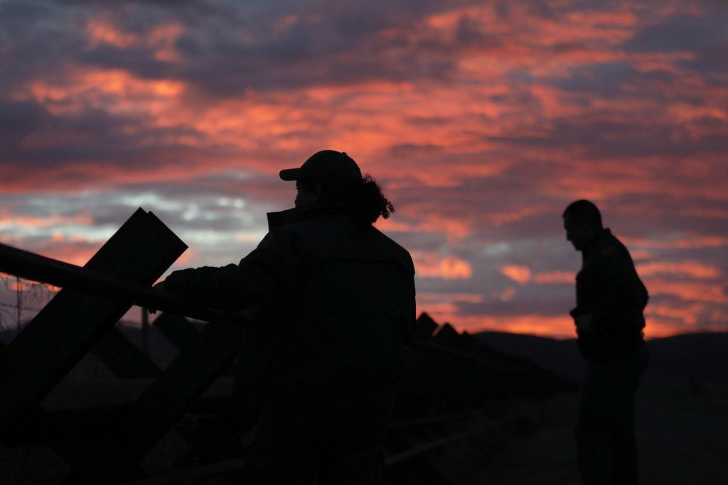 U.S. Border Patrol agents check for footprints near a "Normandy"-style border fence at the...