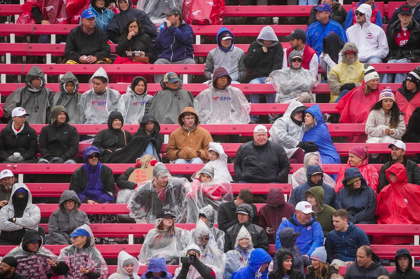 SMU fans cover up against a cold rain during the first half of an NCAA football game against...